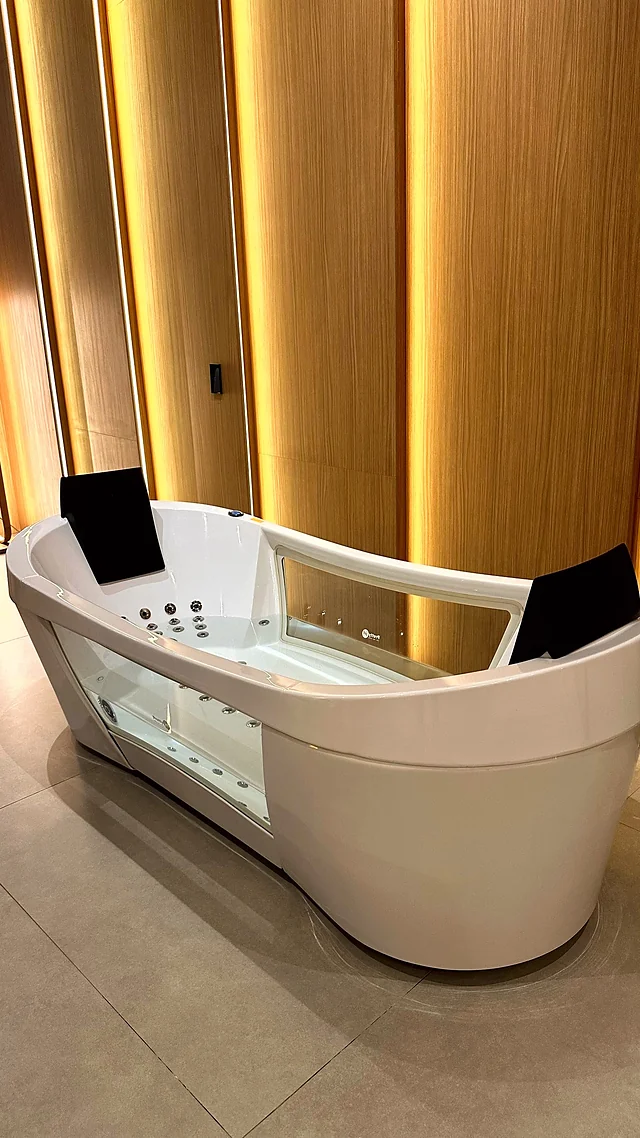 Banheira de hidromassagem branca em banheiro com painéis de madeira e fitas de LED